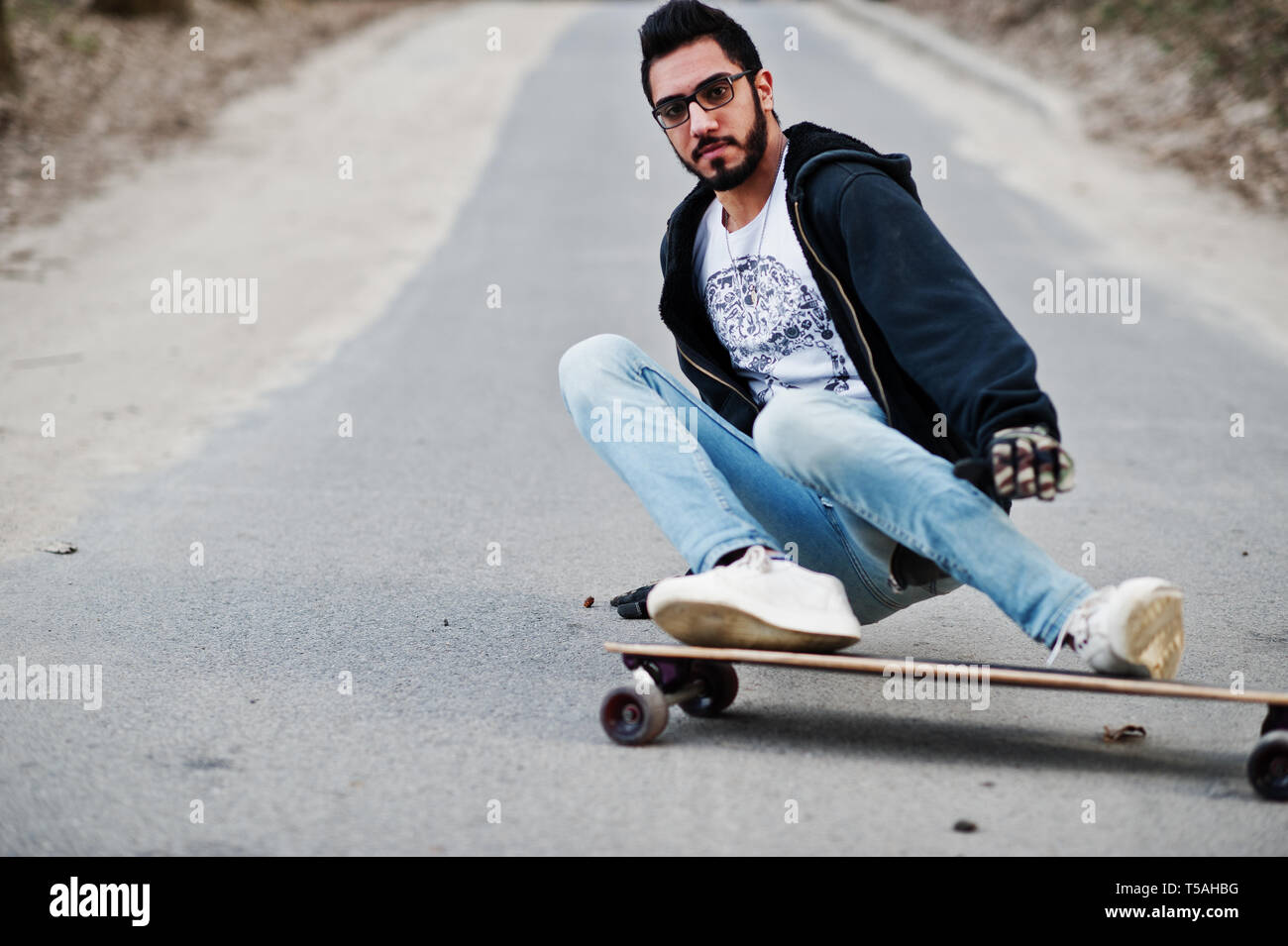 Street style arab man in eyeglasses with longboard longboarding down the  road Stock Photo - Alamy