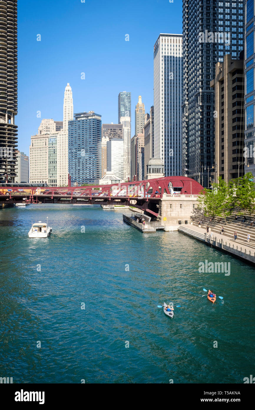 People doing kayaking on Chicago River next to the Riverwalk and Clark