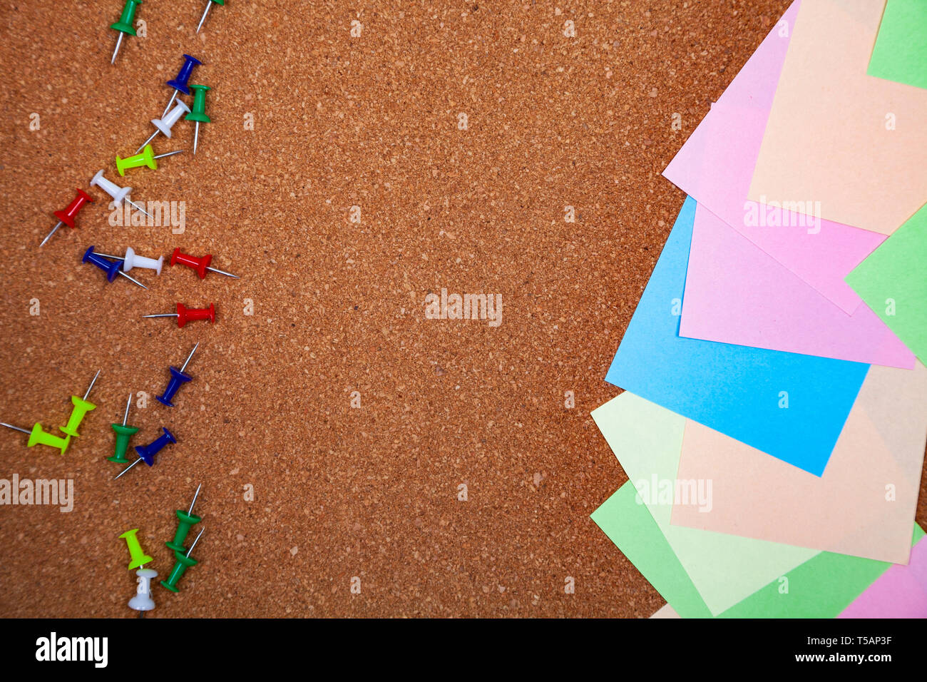 Corkboard with notes. Colored paper on corkboard. Stock Photo