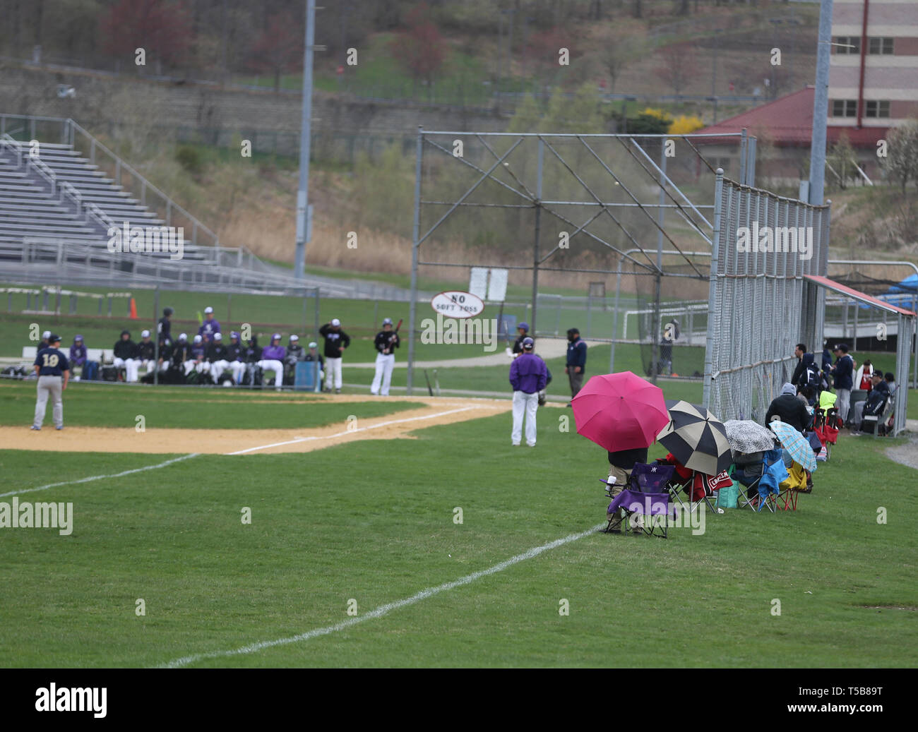 Spectators watching a high school baseball game in the rain Stock Photo