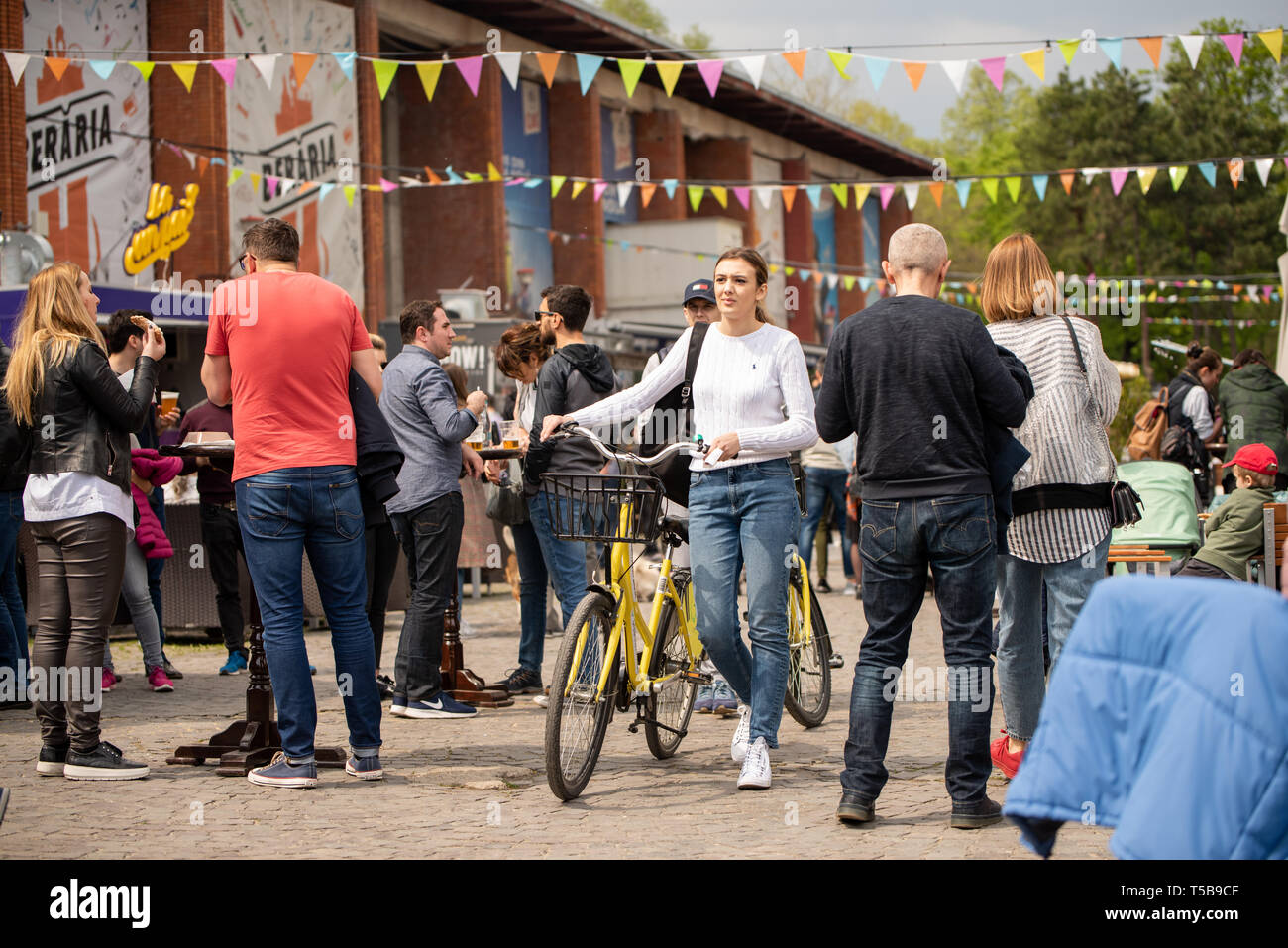 Bucharest, Romania: 21.04.2019 - Street Food Truck festival - Girl carrrying a bike at a street food truck festival in the park in the middle of a crowd. Adult and children fun weekend at the fair. Stock Photo