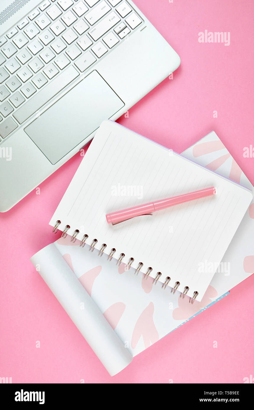 Ultra feminine cluttered pink desk workspace with touch screen laptop closeup, overhead flatlay. Stock Photo