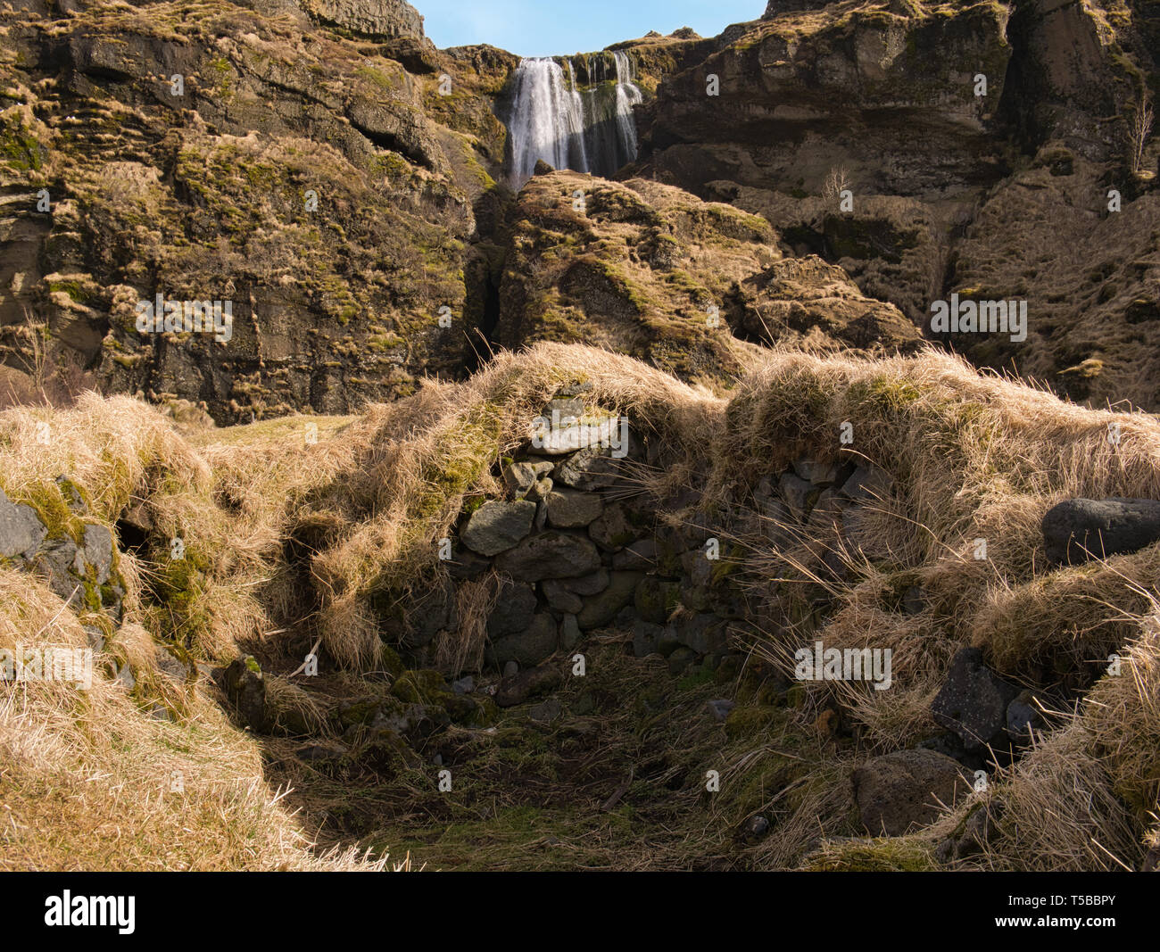 Grad overgrown stone wall in front of the Gljufrabui waterfall in Iceland Stock Photo