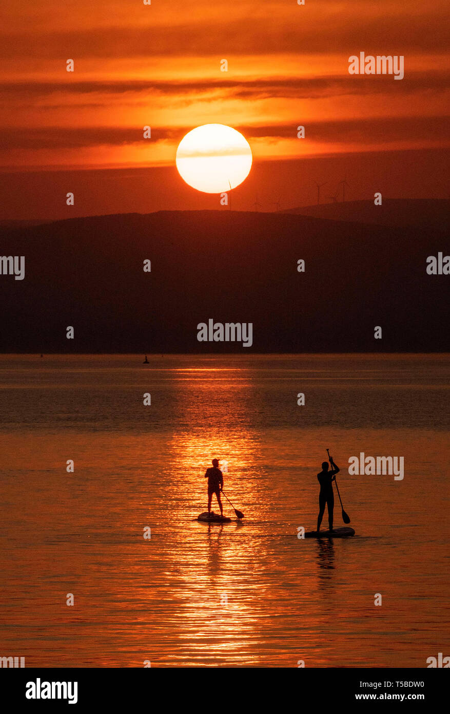 Paddleboarders making the most the stunning  Easter weekend sunrise near the small village of Mumbles near Swansea this morning as the area is bathed  Stock Photo