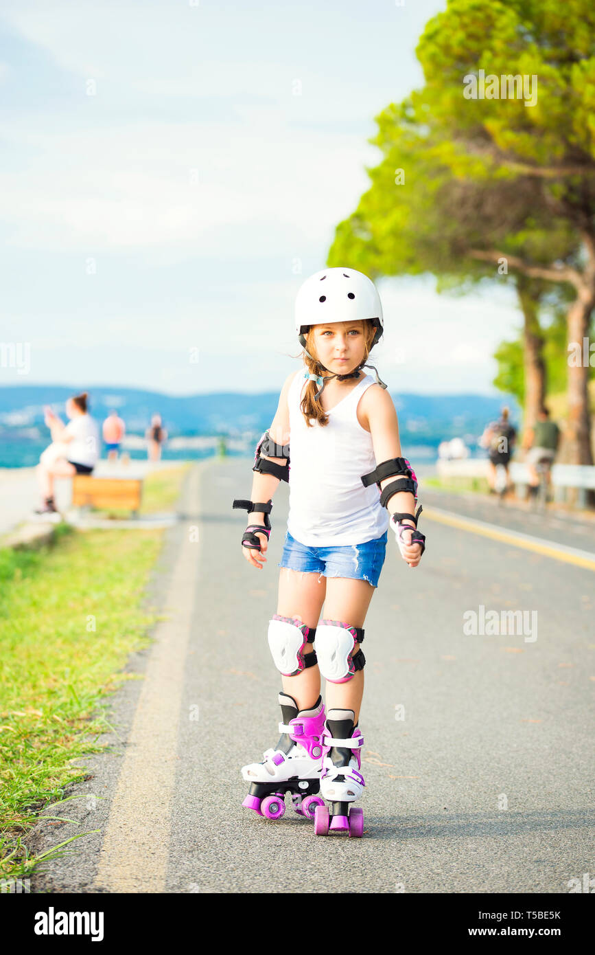 A little caucasian girl beginner roller on the seaboard. Rollerblading and outdoor activity concept Stock Photo