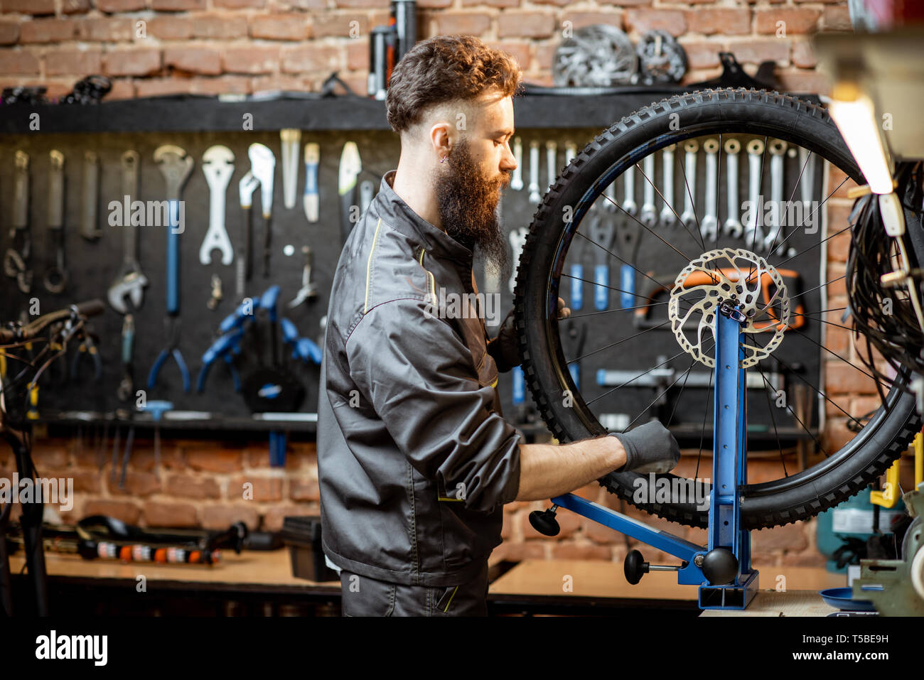 Bicycle service worker aligning wheel with special tool at the