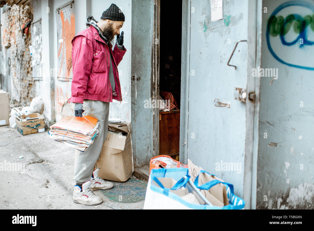 Homeless beggar bringing waste paper to the collection point. Way of ...