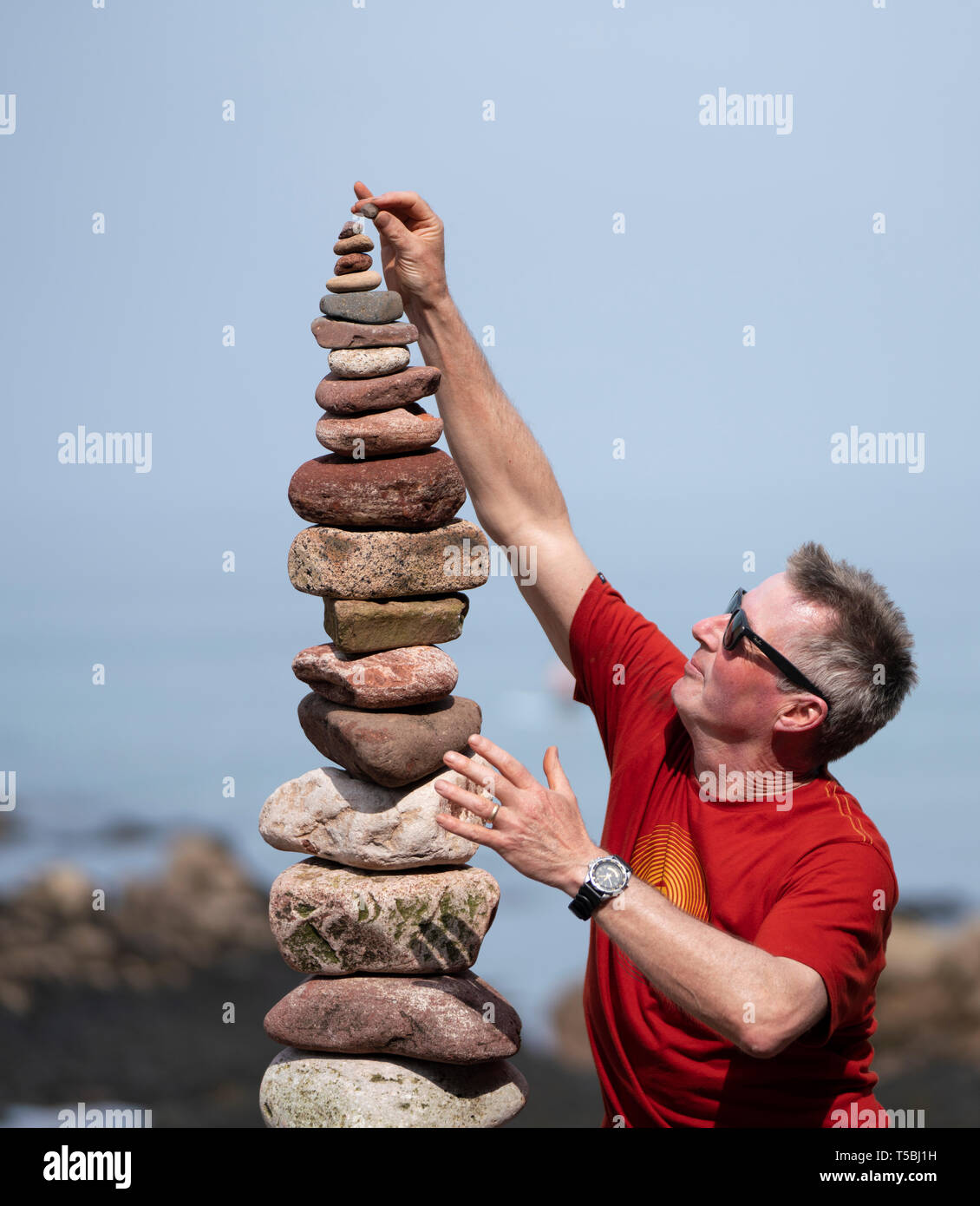 Detail of man making a tall stone stack Stock Photo