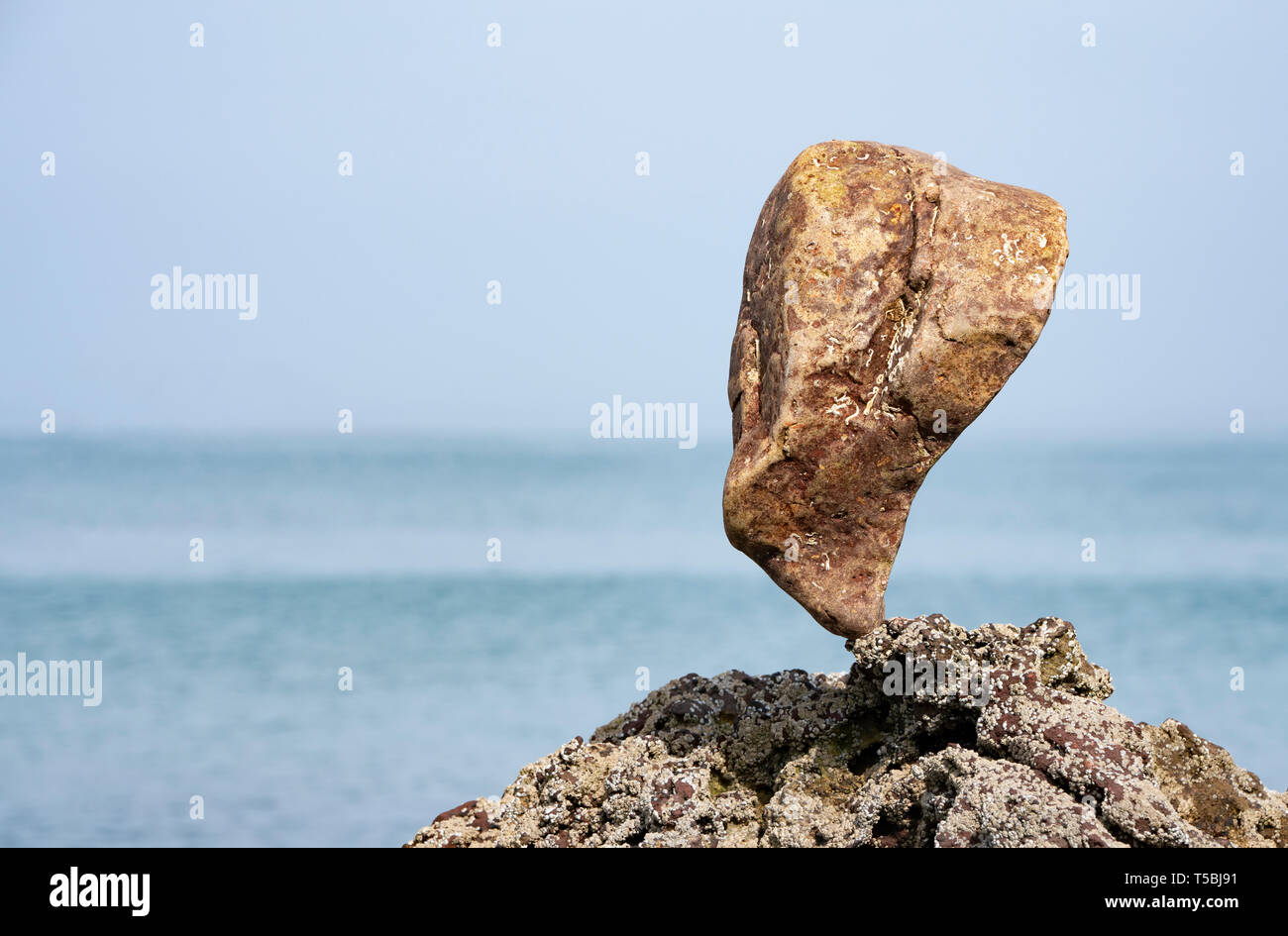 Single large stone balanced on rocks Stock Photo