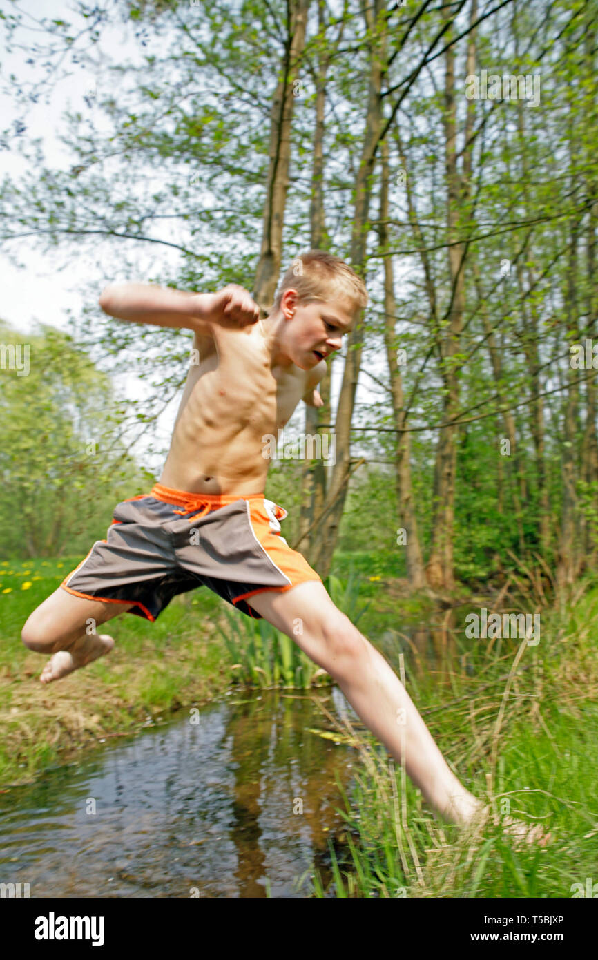 teenage boy jumping barefoot across a stream Stock Photo Alamy
