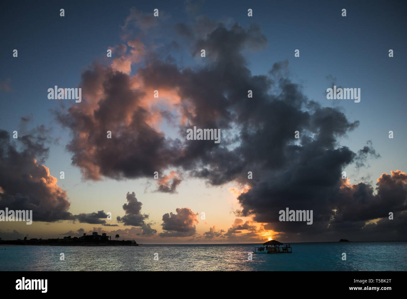 The sun sets behind a floating beach bar in Antigua Stock Photo