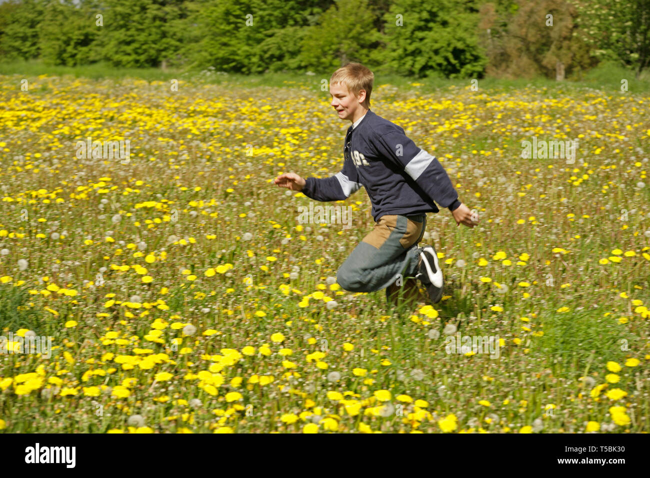 teenage boy running across meadow Stock Photo
