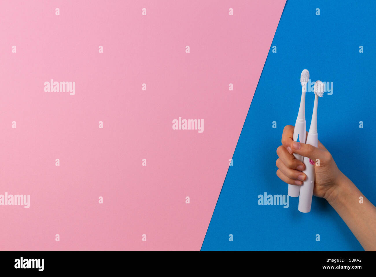 Kid hands with electric toothbrushes on blue background Stock Photo