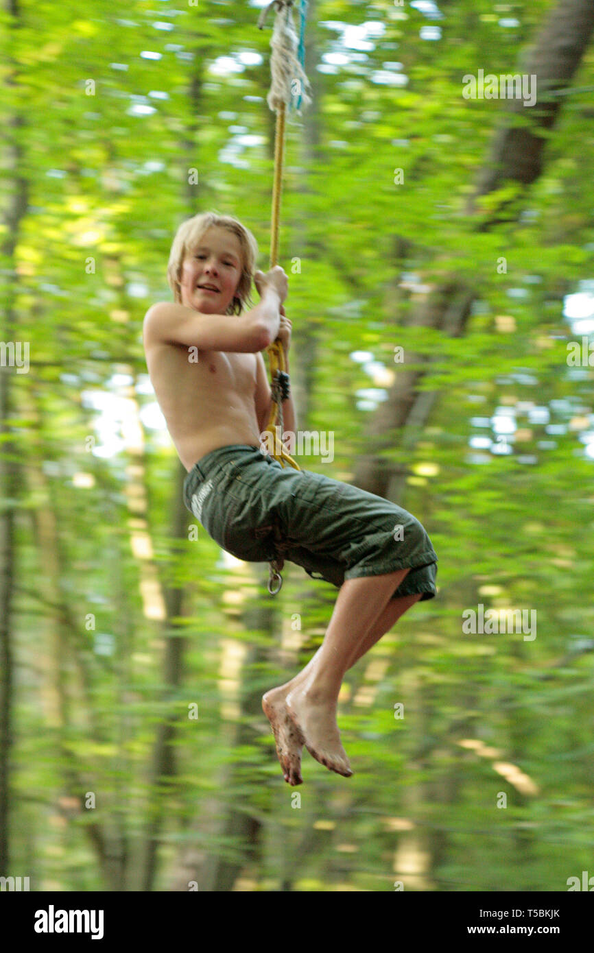 young boy swinging on a rope Stock Photo Alamy