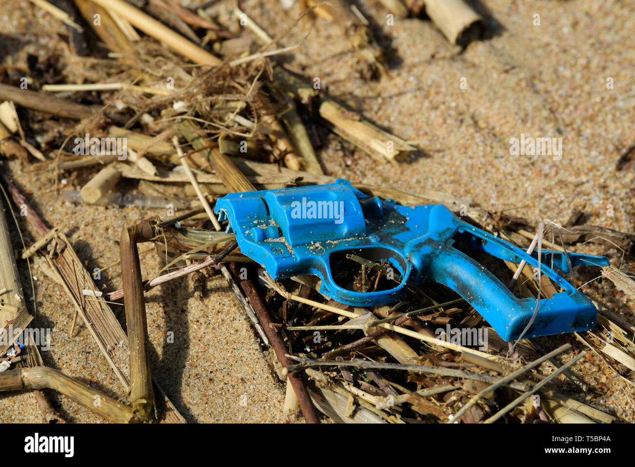 Broken toy gun, plastic and plant flotsam washed up on beach, objects