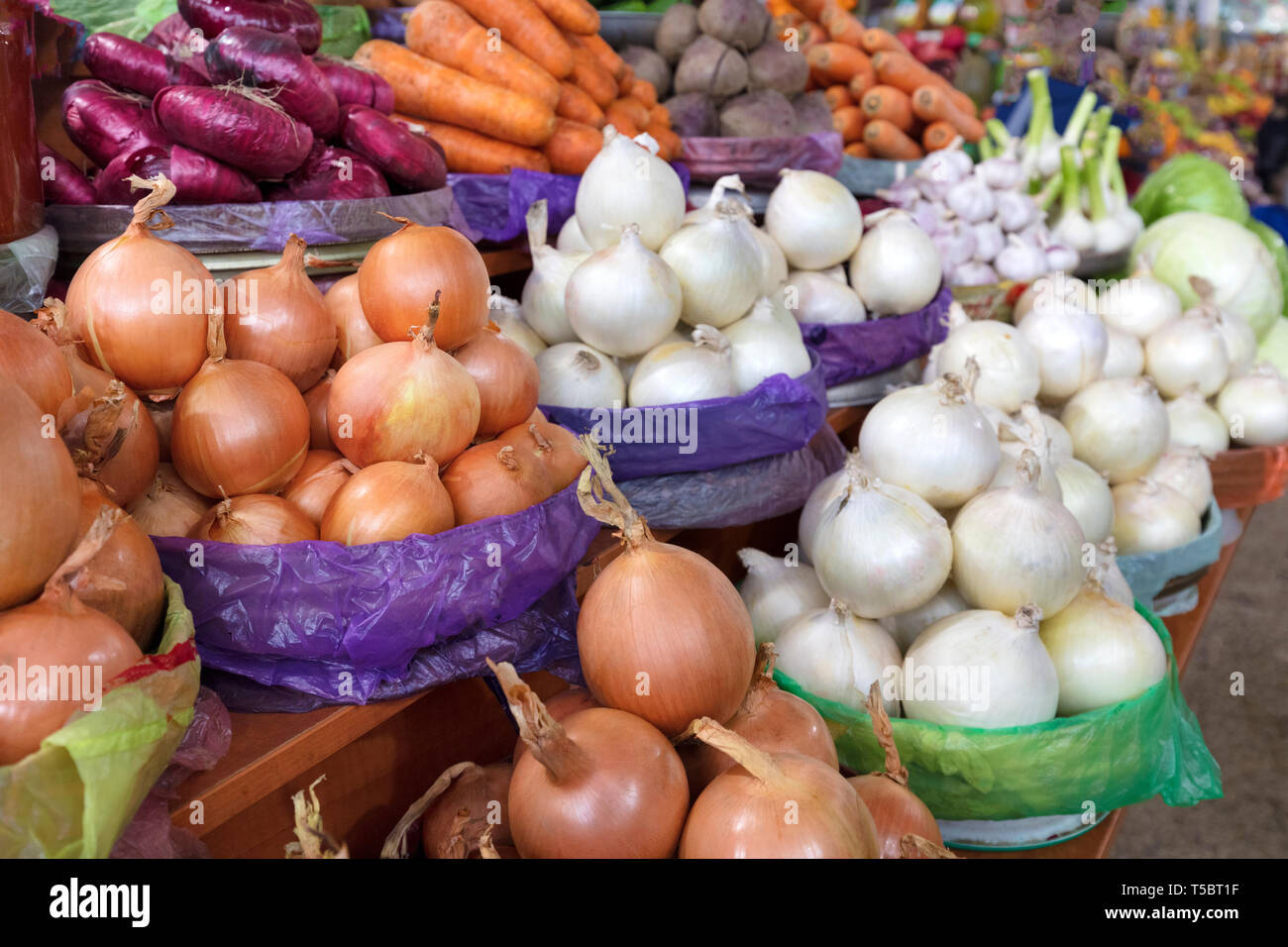 different varieties of onions and other vegetables for sale on the