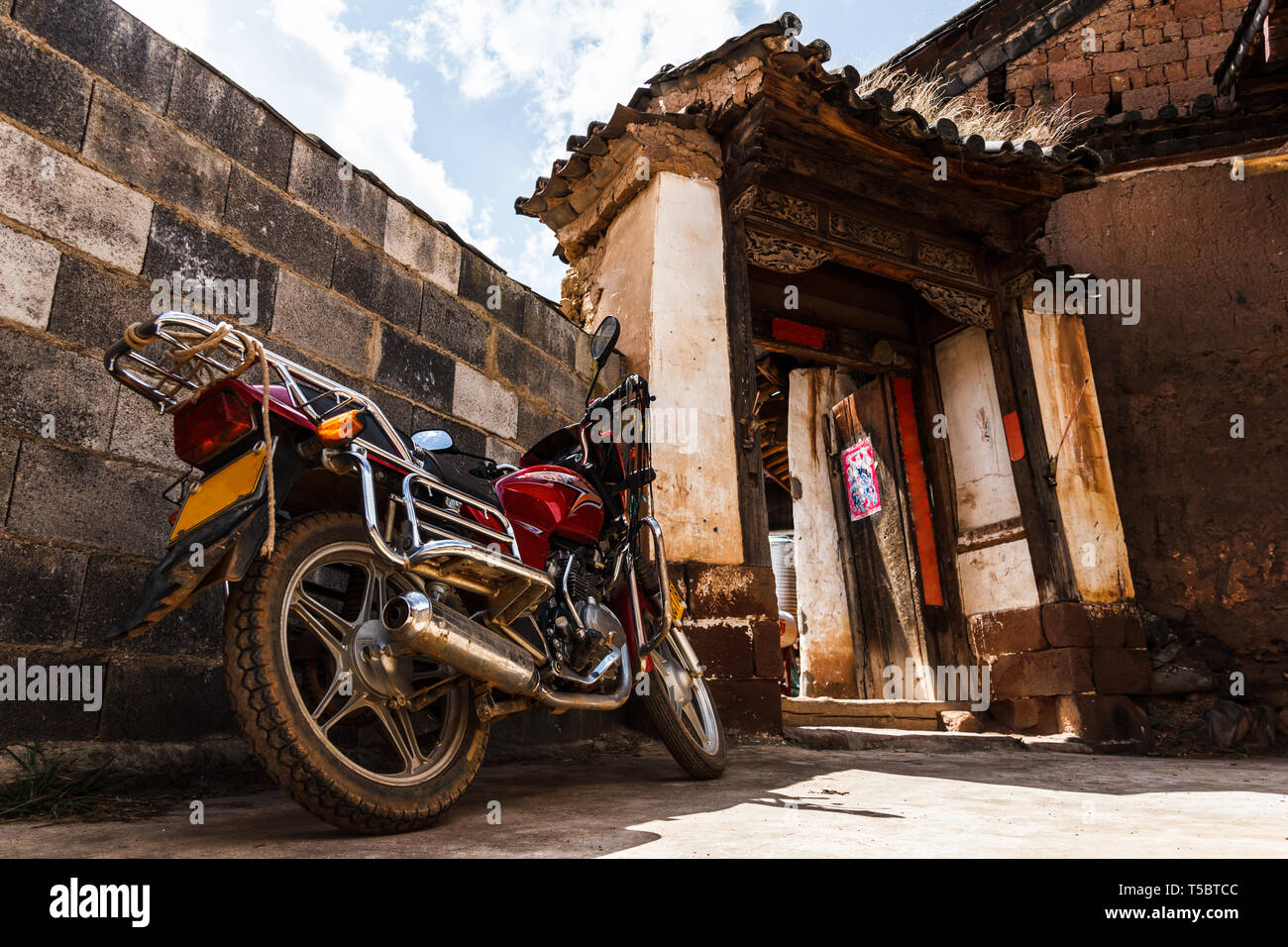 Old school motorbike parked in front of a house in a village Stock Photo