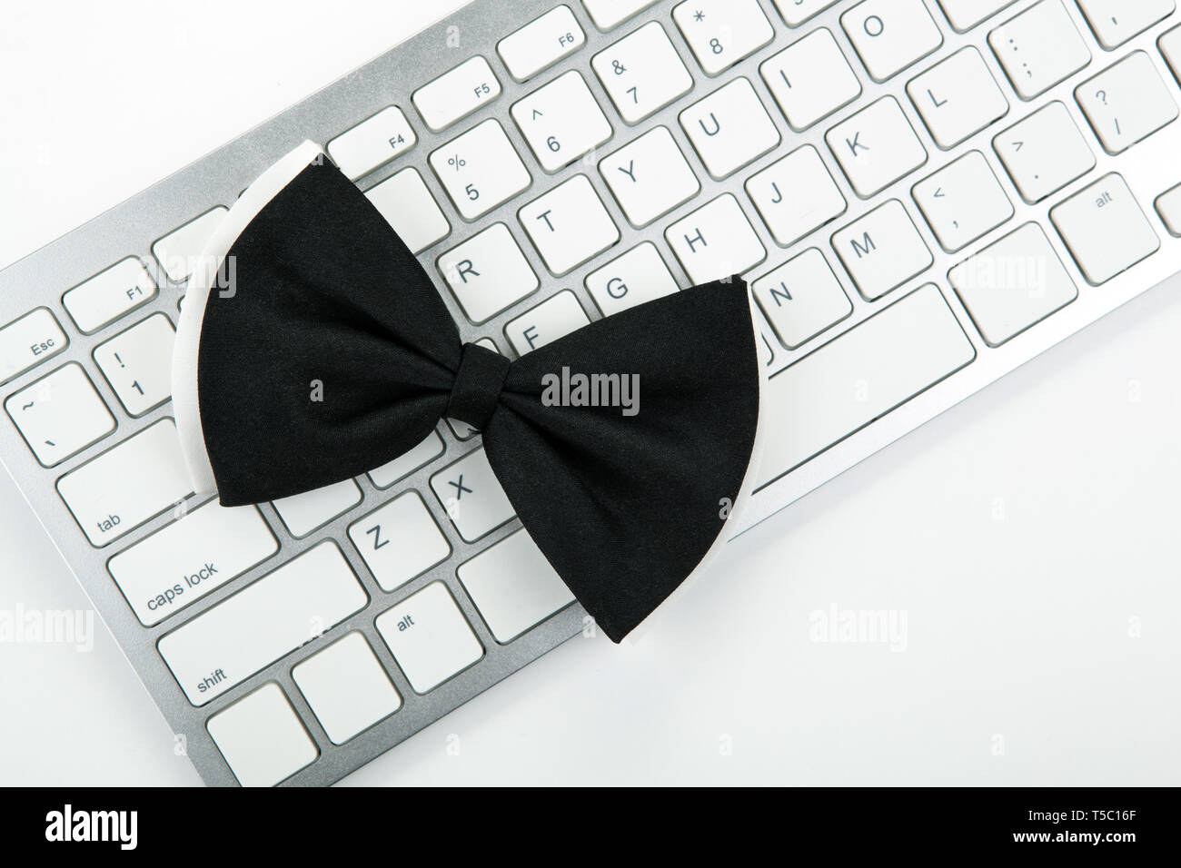 black bow-tie on a white computer keyboard top view Stock Photo