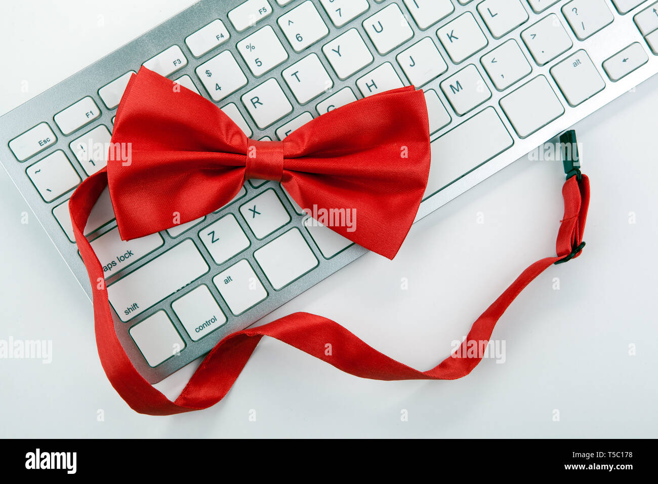red bow-tie on a white computer keyboard top view Stock Photo