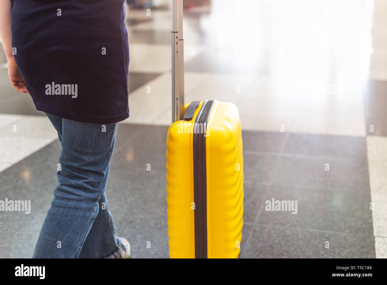 Girl is in the airport with bright and stylish cabin size suitcase as