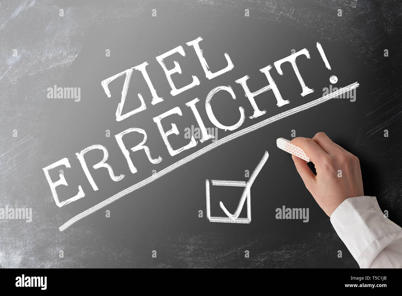 words ZIEL ERREICHT, German for goal accomplished,  with checkmark on blackboard Stock Photo