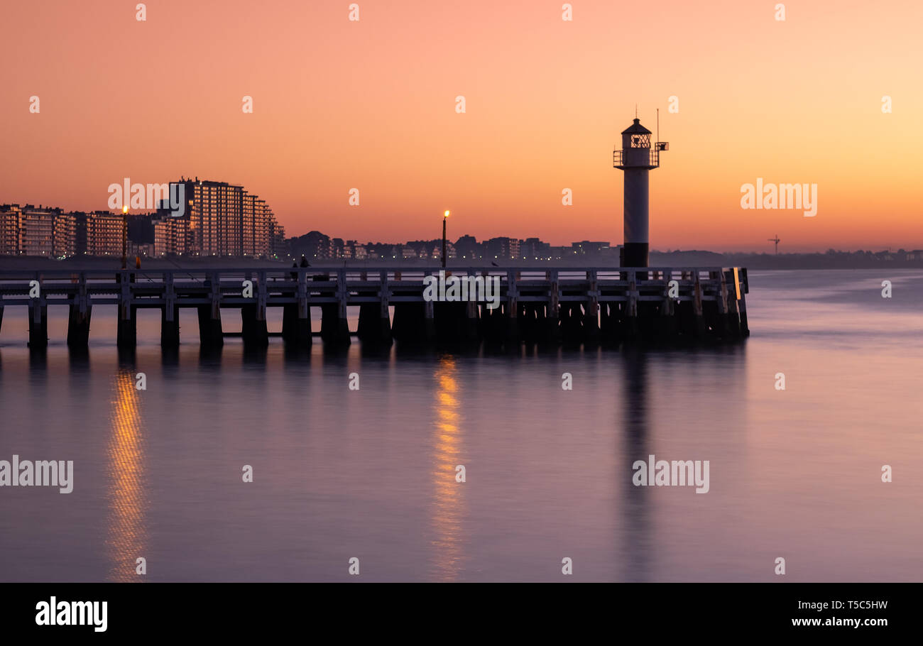 Long exposure image of the Nieuwpoort pier and lighthouse at sunset Stock Photo