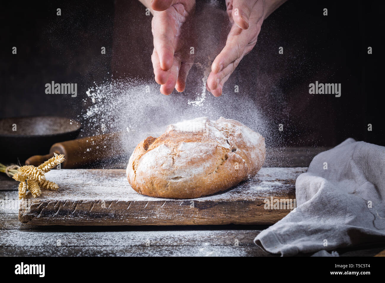 Baker cooking bread. Man slaps flour over the dough. Man's hands Making bread Stock Photo