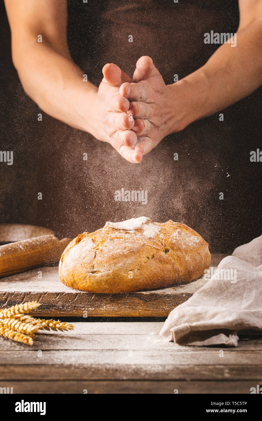 Baker cooking bread. Man slaps flour over the dough. Man's hands Making bread Stock Photo