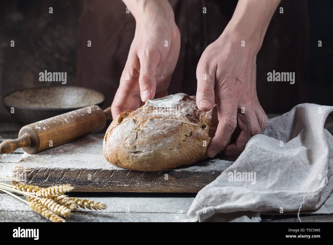 Baker cooking bread. Man slaps flour over the dough. Man's hands Making bread Stock Photo
