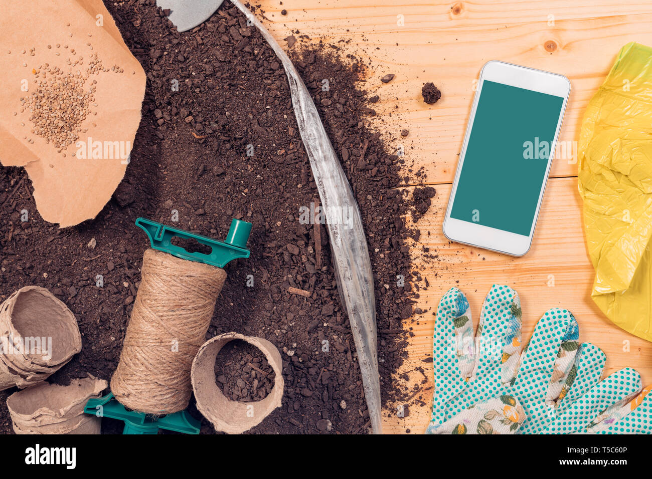 Smartphone screen mock up for gardening and seeding app with tools and equipment on potting soil Stock Photo