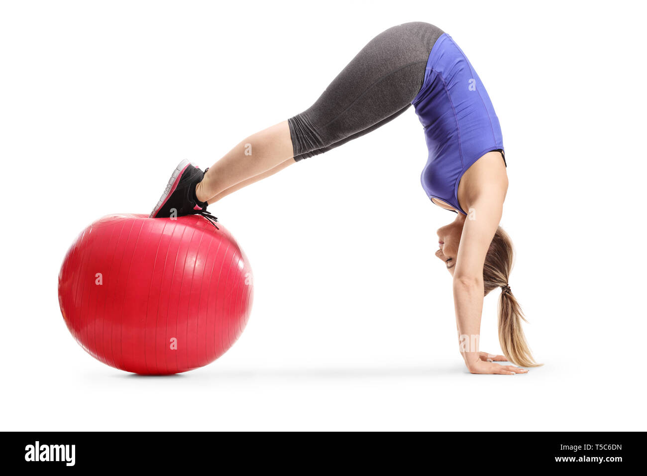 Full length shot of a fit young woman balancing on a fitness ball and practicing handstand isolated on white background Stock Photo
