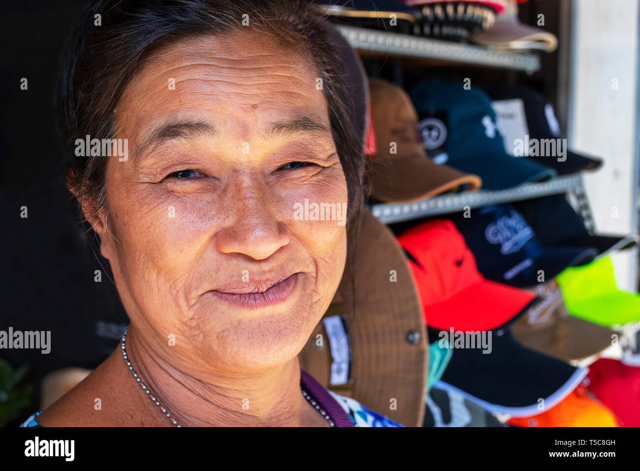 Local Vietnamese woman selling caps from a street stall near the local market, Ho Chi Minh City, Vietnam, Asia Stock Photo