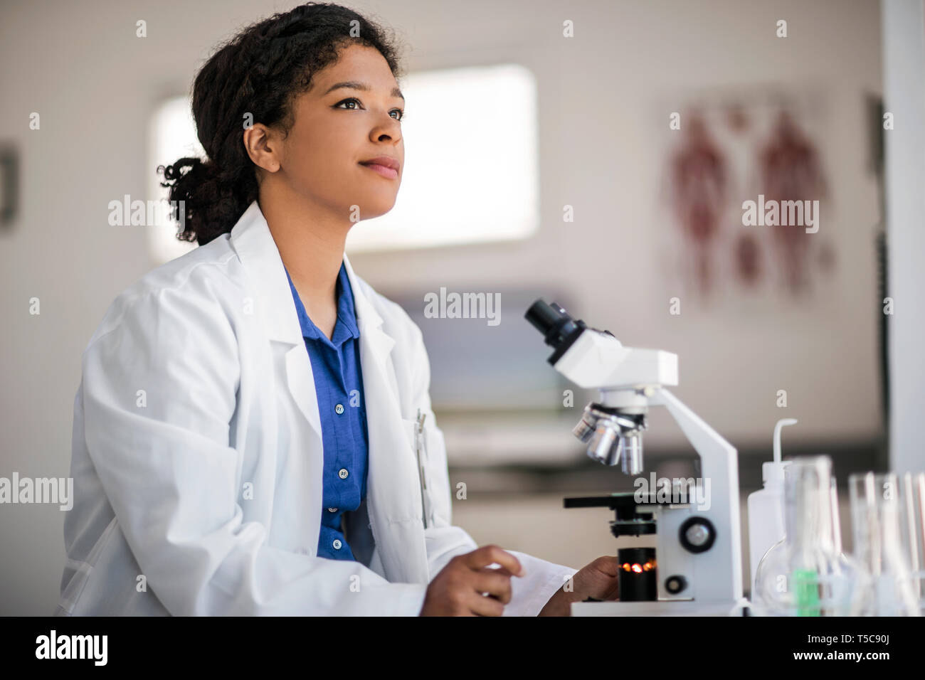 Scientist sitting in her laboratory with her microscope. Stock Photo