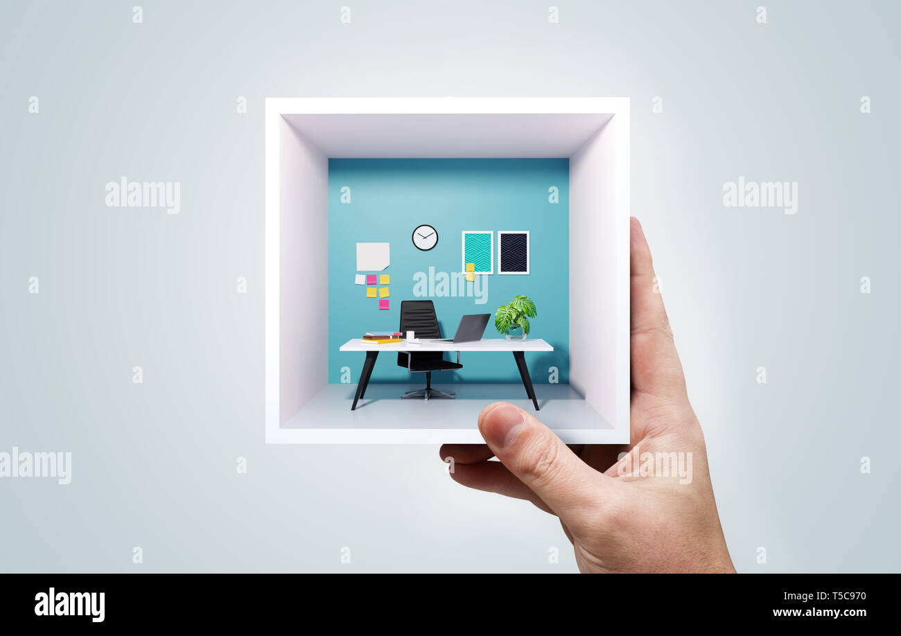 A businessman holding up a miniature square office in his hand. Portable co-working work space business concept. Mixed media image. Stock Photo
