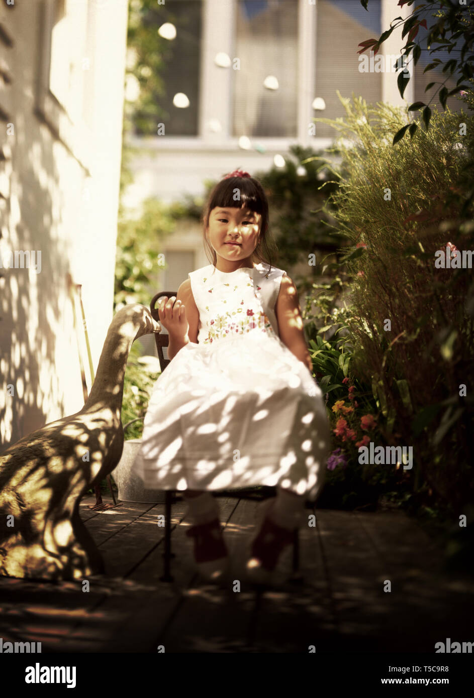 Front view of a little girl sitting on a chair Stock Photo - Alamy
