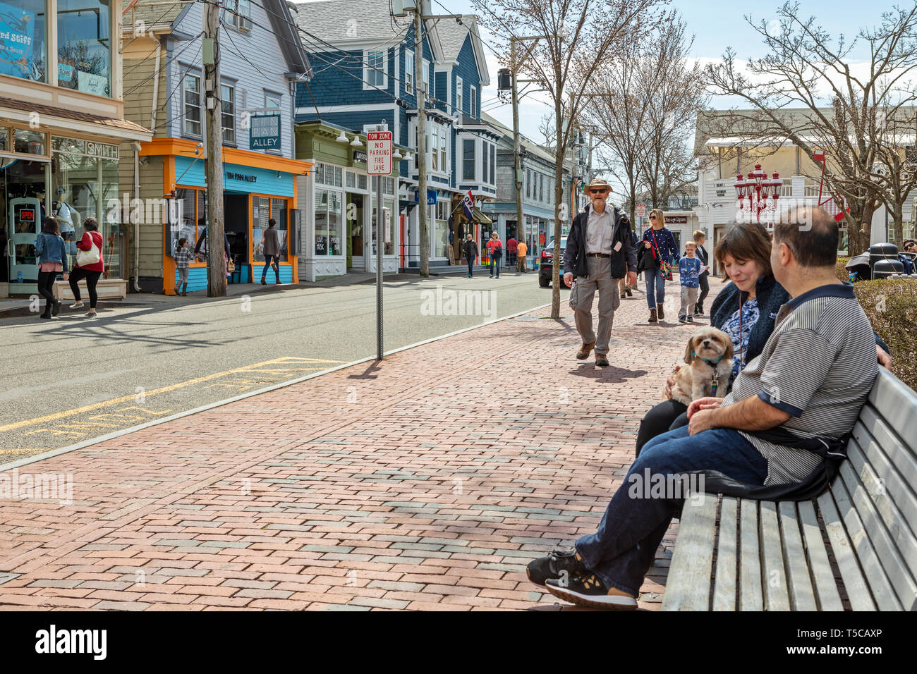 People sitting on a bench, watching people on a beautiful day. Stock Photo