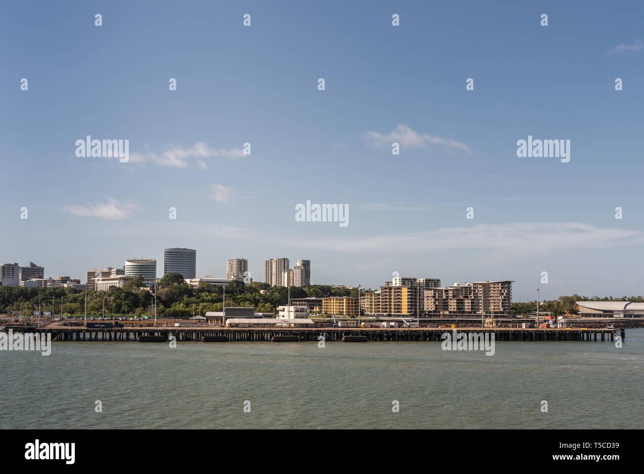 Darwin Australia - February 22, 2019: Darwin skyline seen from south upon harbour bay water under blue sky. Convention center to the right. Dock for l Stock Photo