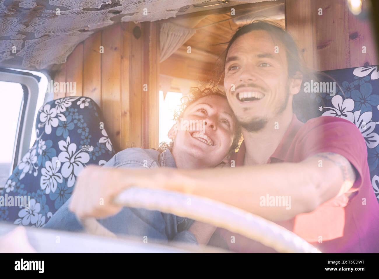 Happy smiling couple inside a vintage minivan - Travel people excited driving for a road trip with a van camper Stock Photo