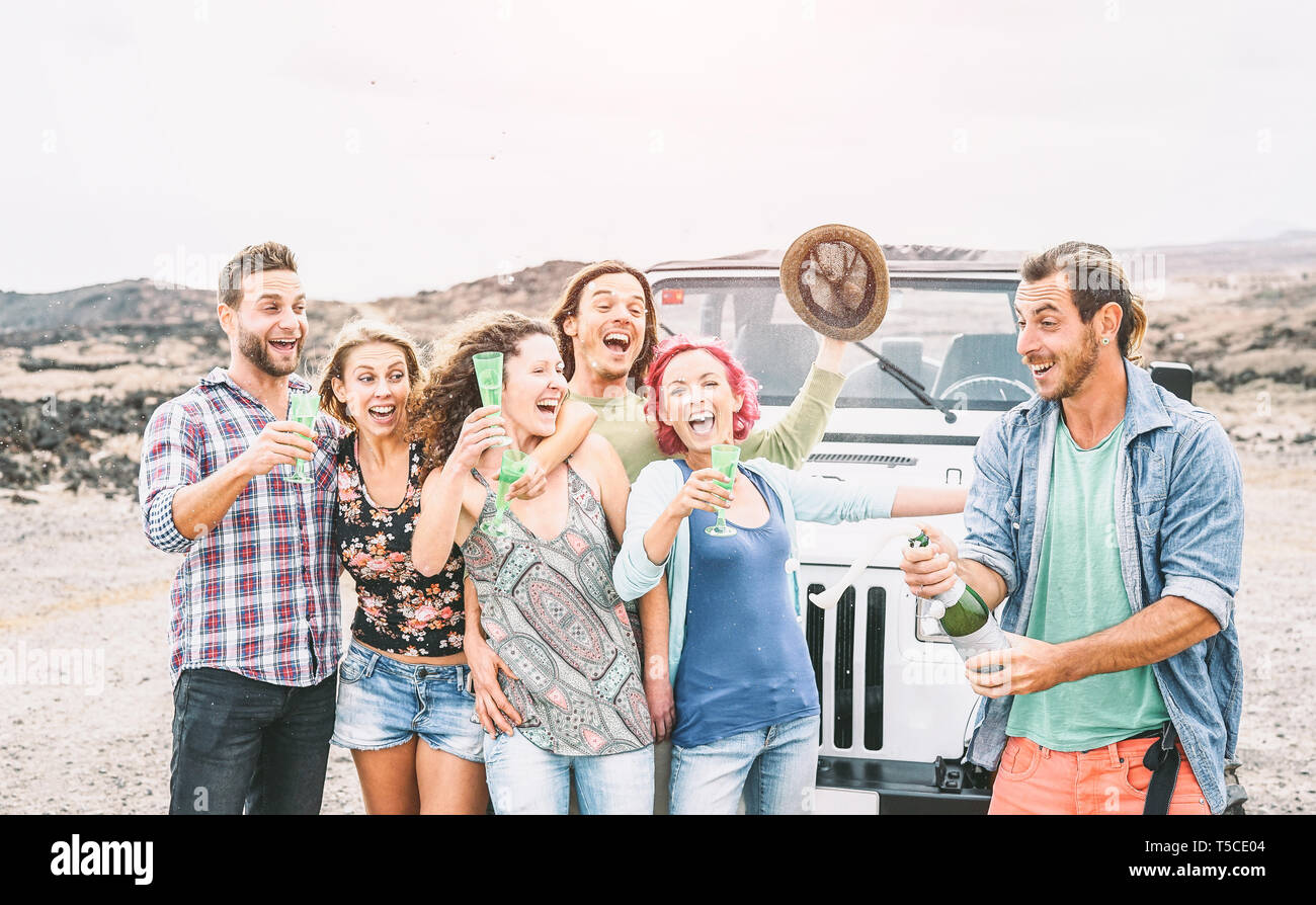 Group of happy friends making party in desert - Travel people having fun drinking champagne prosecco during their road trip with jeep car Stock Photo