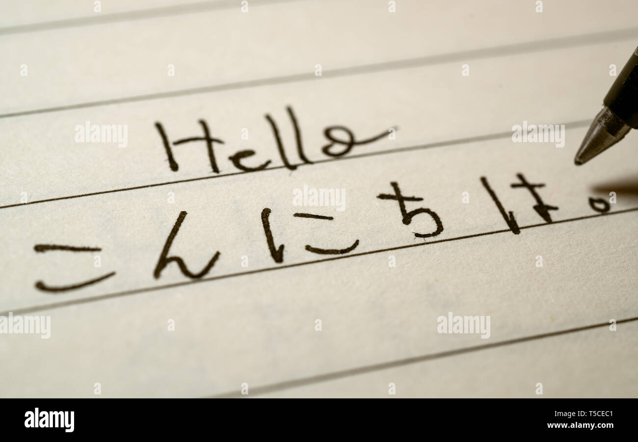 Beginner Japanese language learner writing Hello word in Japanese hiragana characters on a notebook close-up shot Stock Photo