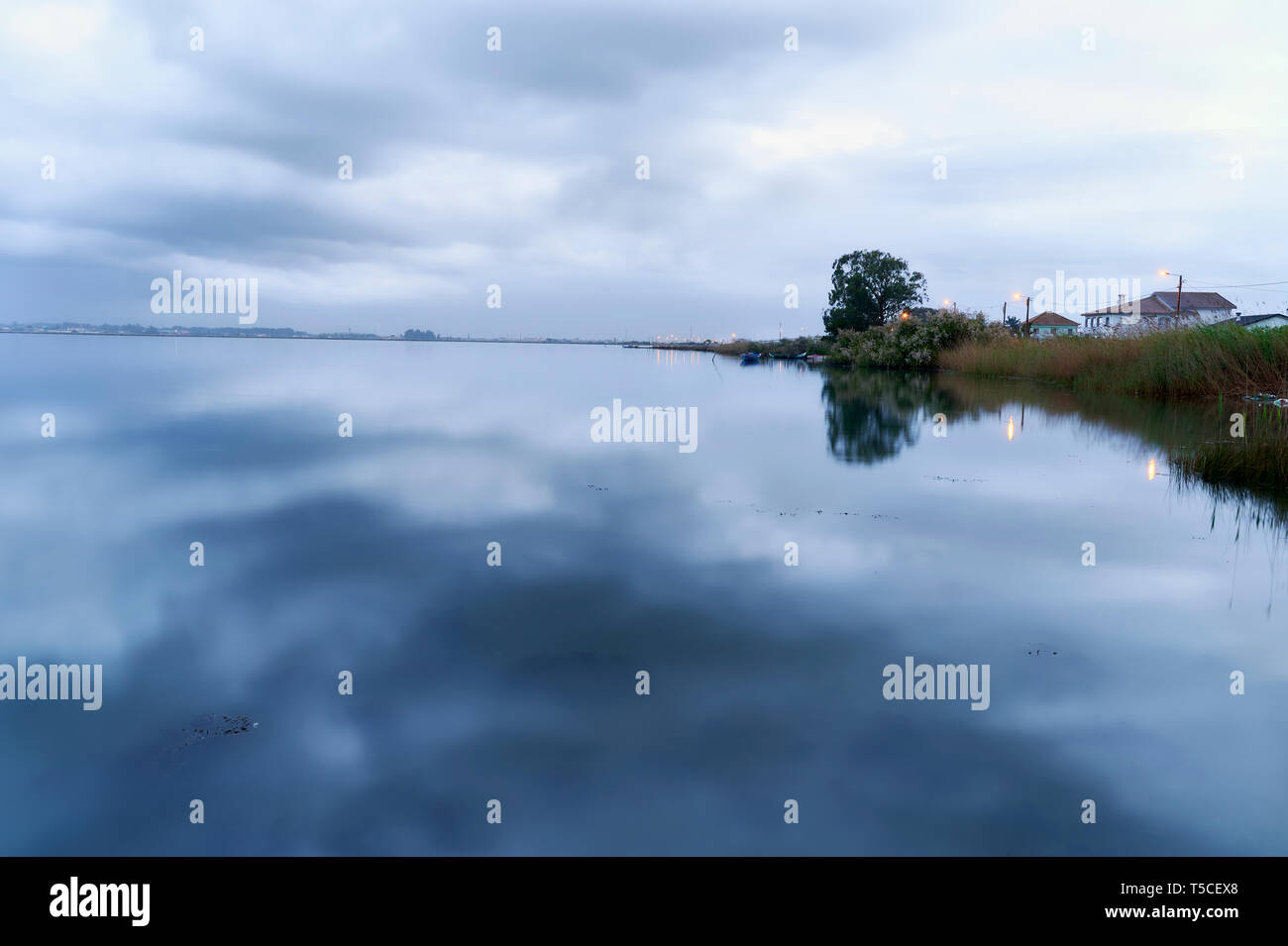Shore and cloudy winter sky, are reflected in the lake surface ant blue hour in Torreirra, Aveiro Lagoon, Portugal Stock Photo
