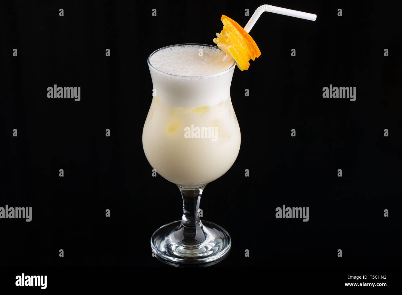 Pina Colada Cocktail - sweet cocktail made with rum, coconut cream or coconut milk garnished with pineapple wedge on black background, selective focus Stock Photo