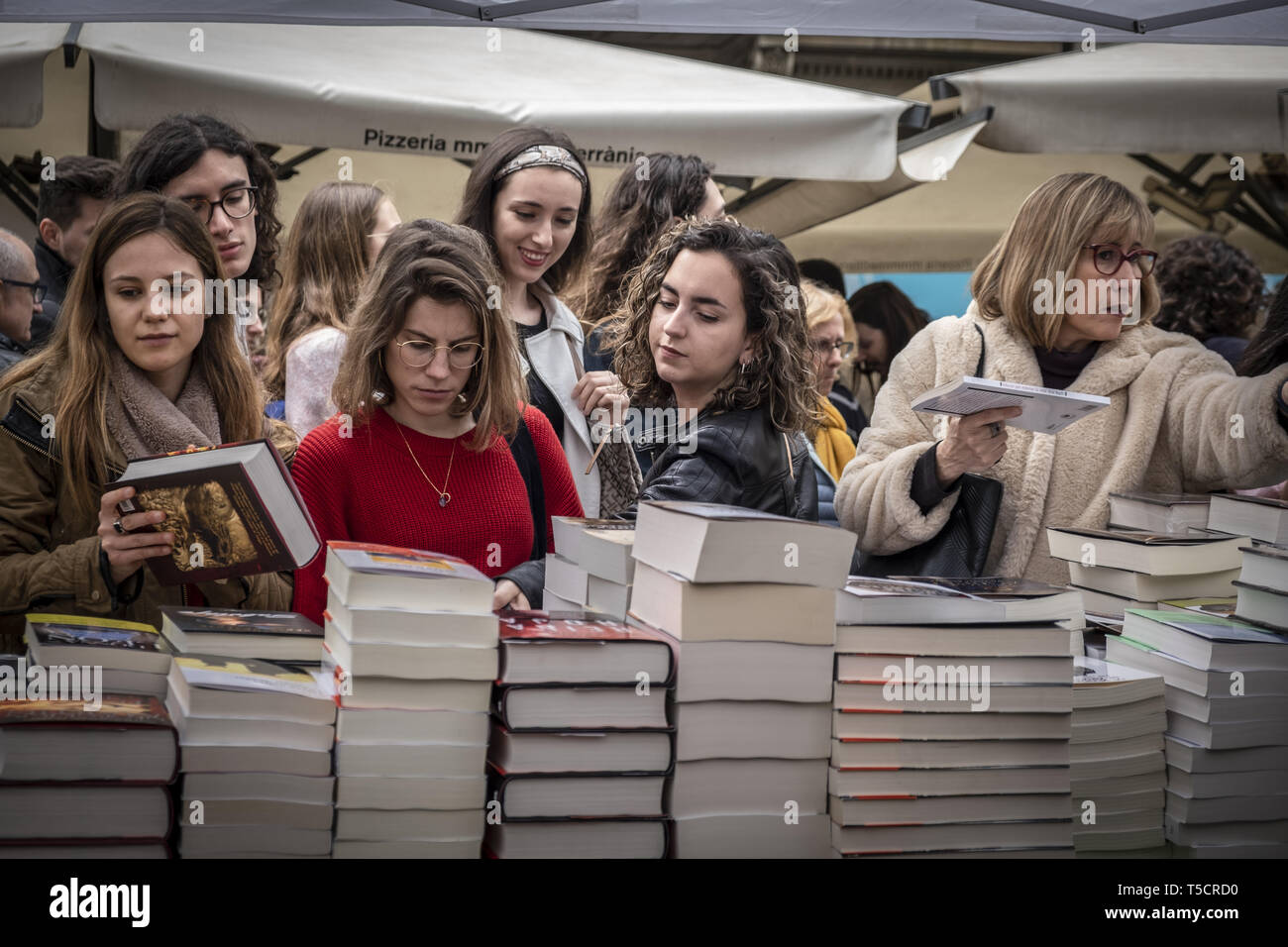 Barcelona, Catalonia, Spain. 23rd Apr, 2019. A group of women are seen looking at some of the books displayed for sale during the Sant Jordi day celebration.The festivity of Sant Jordi is celebrated in conjunction with Book Day and the Fair of Roses, symbols of culture and love. Knight Saint Jordi died on April 23, 303.The cult of Saint Jordi was established in Catalonia during the 8th century but it is at the end of the 19th century, with the Catalan Renaixença that installed as the most celebrated patriotic, civic and cultural day in Catalonia. The streets of the cities and towns of Ca Stock Photo