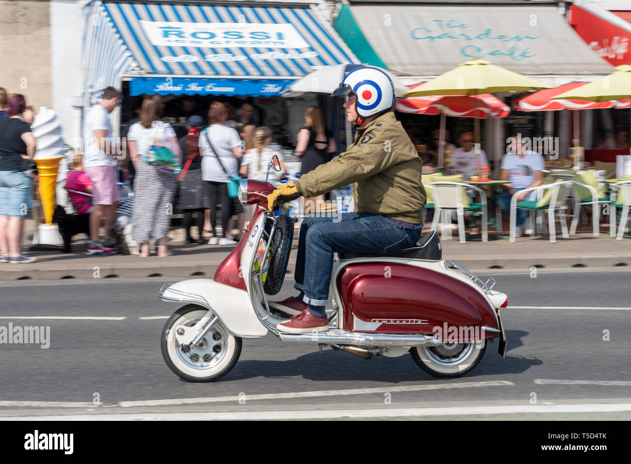 Classic Lambretta motor scooter riding past arches cafes at the