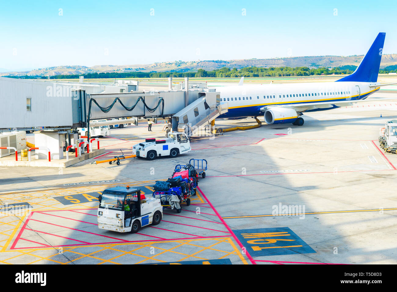 Airport scene, gangway to airplane, service loader cars carrying luggage by airfield, Madrid, Spain Stock Photo