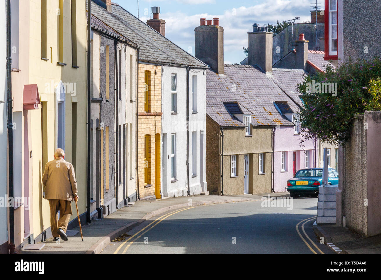 An old man with a stick walks down Mount Pleasant Road, Beaumaris, Anglesey, Wales, UK Stock Photo