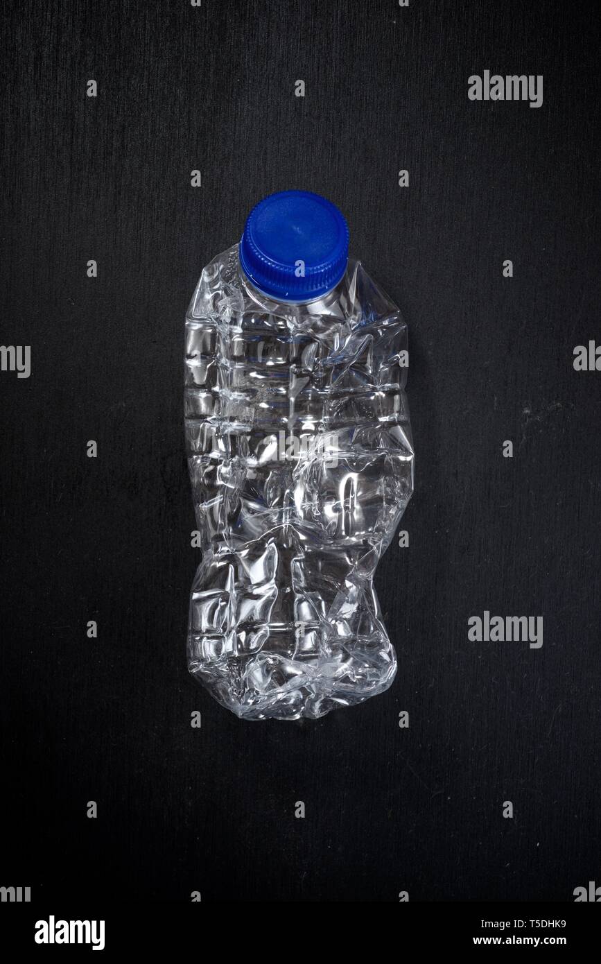 Wrinkled plastic bottle on a black table. Stock Photo