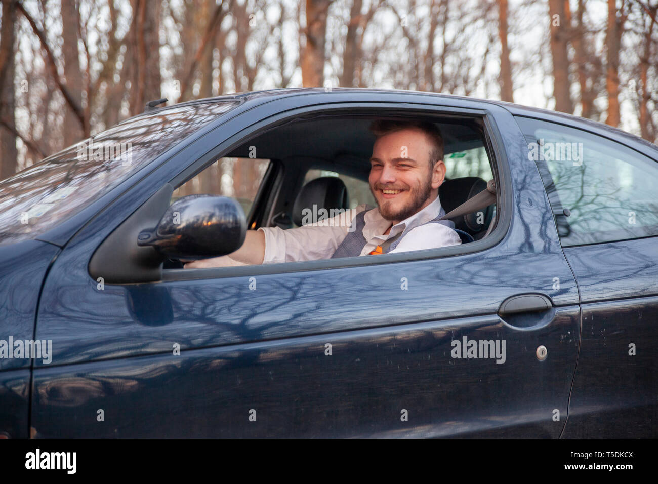 one young man, sitting in drivers seat, head face portrait. shot outdoor thought open window of