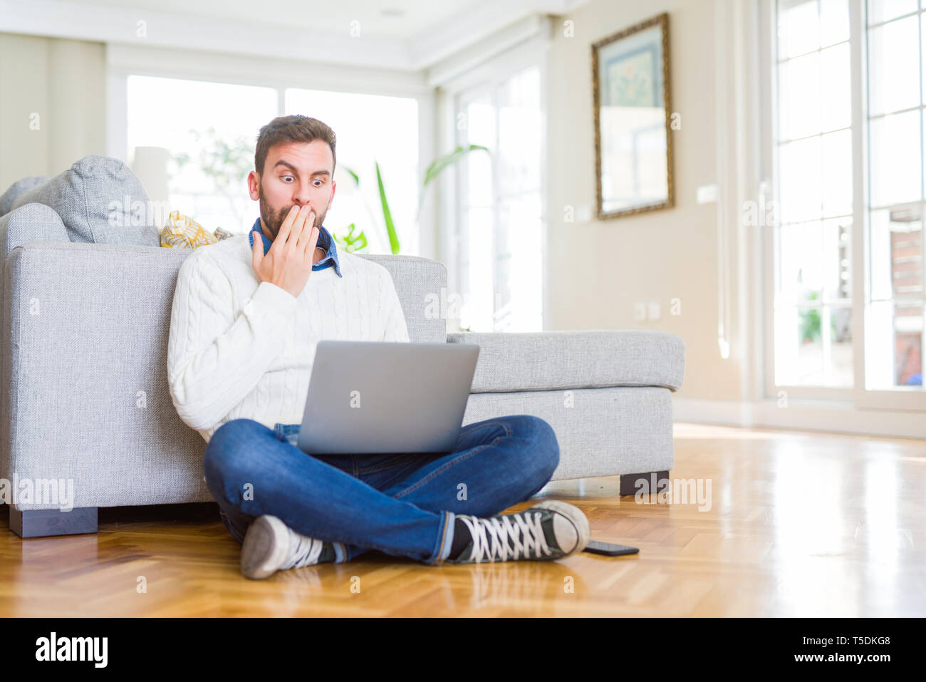 Handsome man wearing working using computer laptop cover mouth with ...