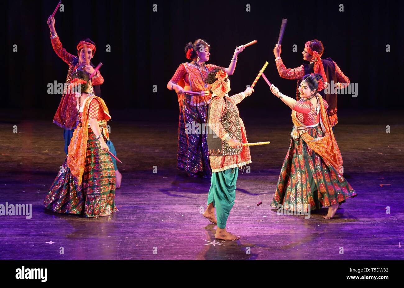 Indian group dancers perform Indian folk dance of Gujarat popularly known as the Dandiya dance or garba wearing traditional dance costumes Stock Photo